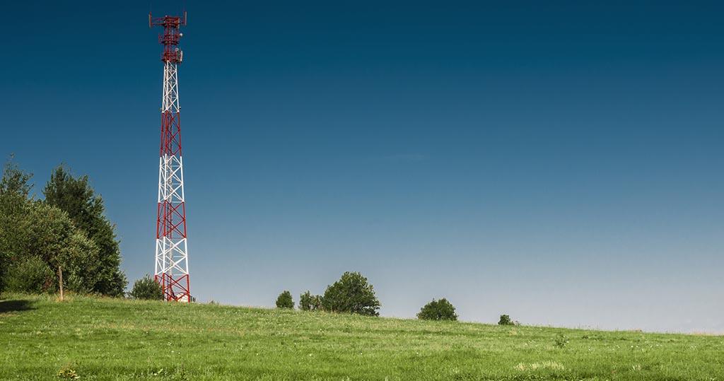 Rural cell tower in green field with blue sky