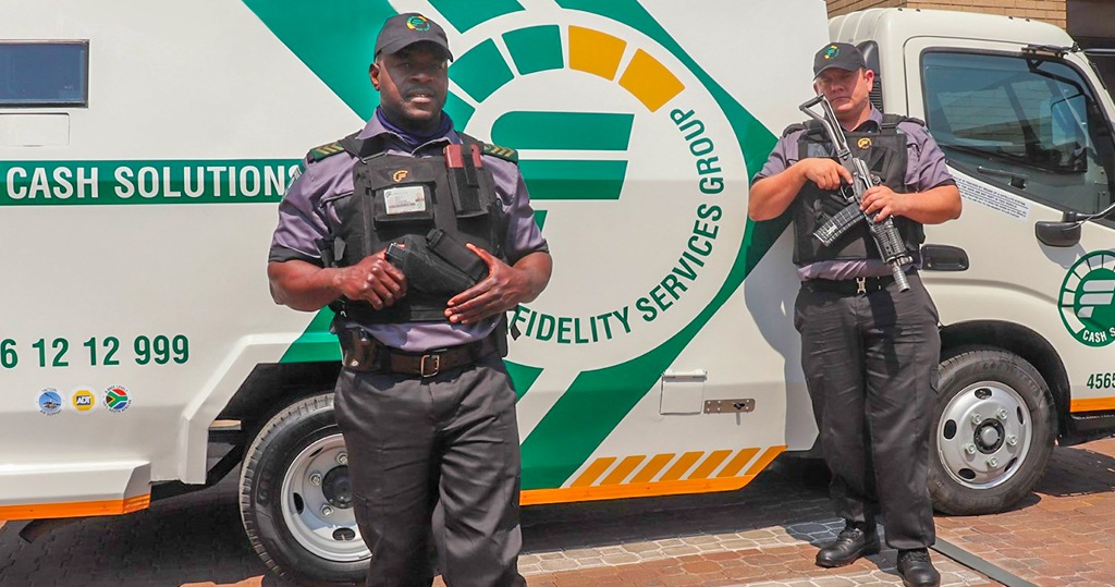 Two-armed security guards stand beside a Fidelity Security truck in South Africa